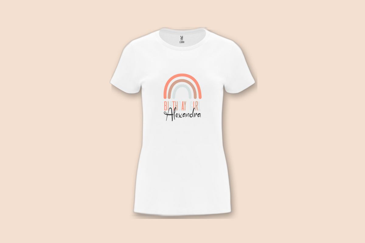 The Slim Rainbow Birthday Girl Tee in white is shown from the front, displaying a subtle rainbow and personalized name.